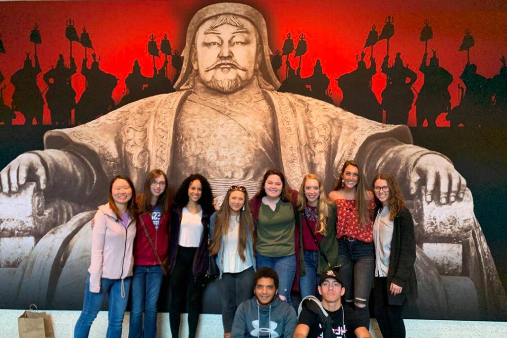 Group of students posing in front of a mural